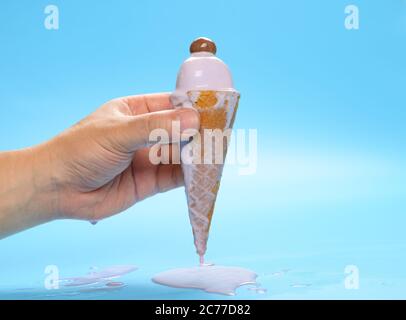 Hand hält eine schmelzende Süßkartoffel Eis-Kegel mit einem Schokoladenbonbon auf der Oberseite Stockfoto