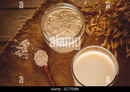 Glas Hafermilch auf einem Holzhintergrund. Laktosefreie pflanzliche Ernährung Milch. Glutenfreier Haferdrink auf braunem Holzgrund. Super Essen - EIN Glas o Stockfoto