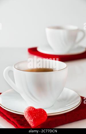 Zwei weiße Tassen Tee auf weißem Hintergrund. Herzförmige Marmelade, Symbol des Valentinstag und Liebe. Das Konzept eines Treffens von zwei Liebenden. Stockfoto