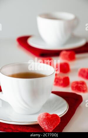 Zwei weiße Tassen Tee auf weißem Hintergrund. Herzförmige Marmelade, Symbol des Valentinstag und Liebe. Das Konzept eines Treffens von zwei Liebenden. Stockfoto