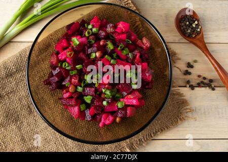 Vinaigrette auf einem hölzernen Hintergrund. Russischer Gemüsesalat mit roten Rüben in einer Schüssel. Rustikales, traditionelles Gericht. Stockfoto