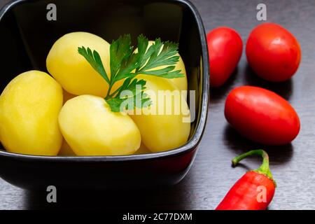 Gekochte Kartoffeln mit Chilischoten und Tomaten auf dunklem Hintergrund Stockfoto