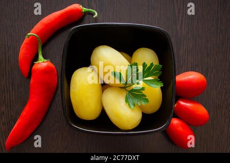 Gekochte Kartoffeln mit Chilischoten und Tomaten auf dunklem Hintergrund Stockfoto