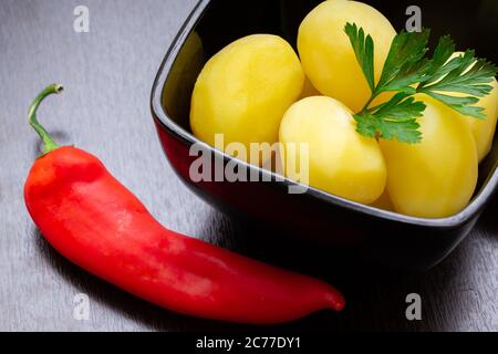 Gekochte Kartoffeln mit Chilischoten und Tomaten auf dunklem Hintergrund Stockfoto