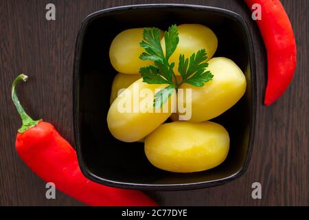 Gekochte Kartoffeln mit Chilischoten und Tomaten auf dunklem Hintergrund Stockfoto