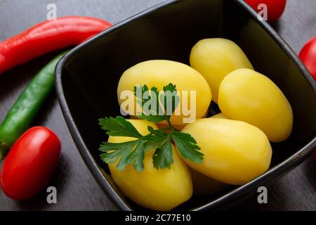 Gekochte Kartoffeln mit Chilischoten und Tomaten auf dunklem Hintergrund Stockfoto