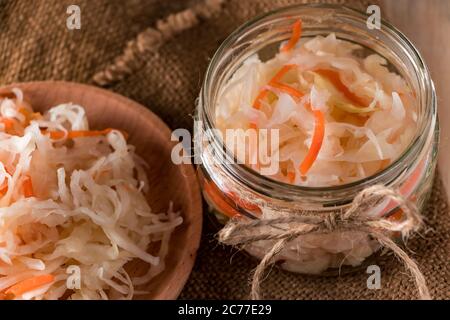 Hausgemachtes Sauerkraut auf Leinenhintergrund. Rustikaler Stil, Gemüsekonserven auf hellem Holzhintergrund. Öko-Lebensmittel, der Trend zu gesunder Ernährung. Stockfoto