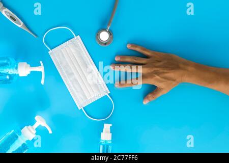 Draufsicht menschliche Hand, Hygienische Masken Digitalthermometer, Stethoskop, Alkoholspray auf blauem Hintergrund. Handmann, medizinische Gesichtsmaske, Alkohol Sanitiz Stockfoto