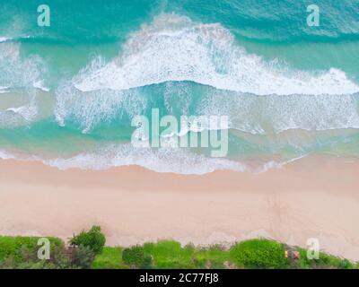 Luftaufnahme von oben schöner topischer Strand mit weißem Sand Kokospalmen und Meer. Blick von oben leerer und sauberer Strand. Wellen krachen leer Strand Fr. Stockfoto