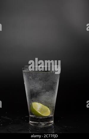 SOAD Wasser in Glas mit Kalk auf schwarzem Hintergrund. Kühles Sodawasser und Kalk mit Kopierraum. Stockfoto