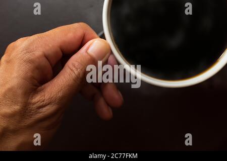 Draufsicht Nahaufnahme Hand Mann halten Kaffeetasse . Schwarzer Kaffee in der Kaffeetasse. Stockfoto