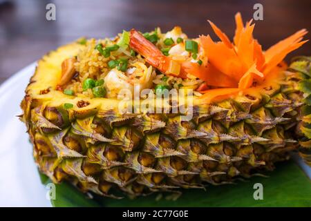 Nahaufnahme Thai Royal Ananas gebratenen Reis. Gebratener Reis mit Garnelen in einer Ananas auf Holztisch serviert. Stockfoto