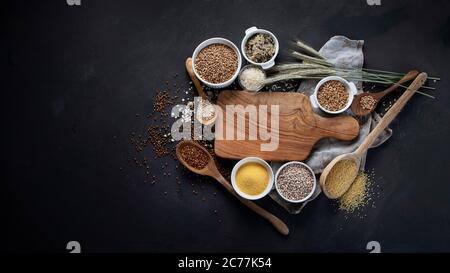 Verschiedene Arten von Getreide in Schalen auf schwarzem Hintergrund. Gesunde Ernährung Essen. Draufsicht mit Kopierbereich Stockfoto