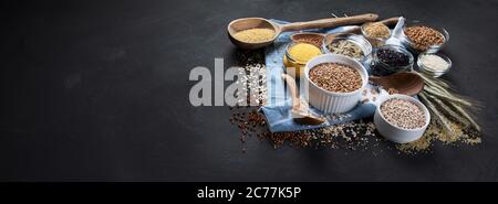 Verschiedene Arten von Getreide in Schalen auf schwarzem Hintergrund. Gesunde Ernährung Essen. Kopieren Raum , Panorama , Banner. Stockfoto