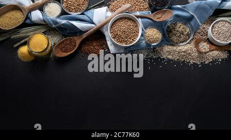 Verschiedene Arten von Getreide in Schalen auf schwarzem Hintergrund. Gesunde Ernährung Essen. Draufsicht mit Kopierbereich. Stockfoto
