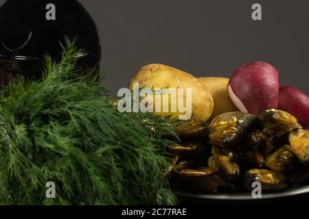 Heringsfilet mit jungen Kartoffeln und OnionJunge Kartoffeln und geräucherter Fisch, Dill auf dem Brett, eine Flasche dunkles Bier Stockfoto