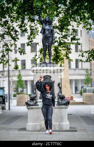 Jen Reid posiert vor ihrer schwarzen Harz- und Stahlstatue mit dem Titel A Surge of Power (jen Reid) 2020 von Marc Quinn, wo sie auf dem leeren Edward Colston Sockel im Stadtzentrum von Bristol installiert wird. Stockfoto