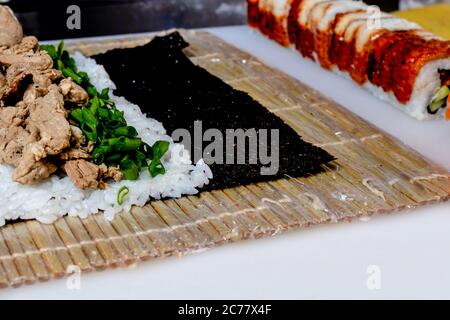 Der Prozess des Kochens von Sushi, die Rolle in einem Nori Blatt wickeln. Japanische Küche. Stockfoto