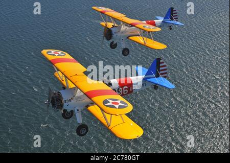 Zwei restaurierte 1940er US Navy Boeing Model 75, N2S Stearman Doppeldecker Trainer über dem Ozean. Stockfoto