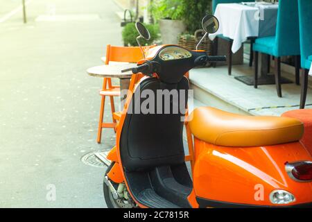 Orange Vintage Roller auf einer Sommer Rom Straße. Vintage Roller in der Nähe eines Sommercafés in der italienischen Stadt. Stockfoto