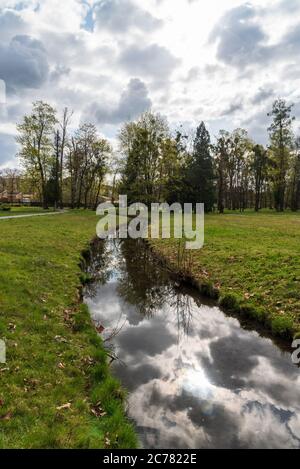 Mlynka Bach mit Himmel und Bäumen Spiegelung auf Park Bozeny Nemcove in Karvina Stadt in Tschechien während des Frühlings Tag Stockfoto