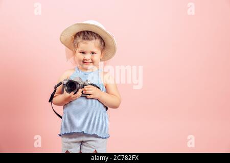 Kleines Mädchen mit alten Vintage Kamera und lächelnd auf rosa Hintergrund. Stockfoto