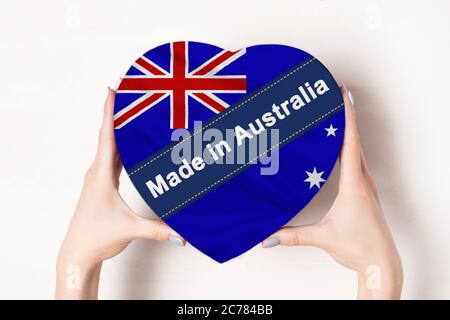 Inschrift in Australien die Flagge von Australien. Weibliche Hände halten eine herzförmige Box. Weißer Hintergrund. Stockfoto