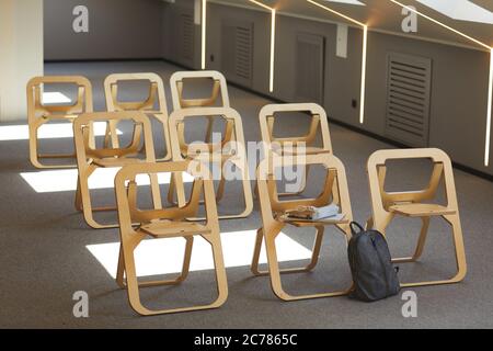 Leerer Hörsaal mit modernen Holzklappstühlen in Reihen und Umhängetasche in der Nähe eines davon Stockfoto