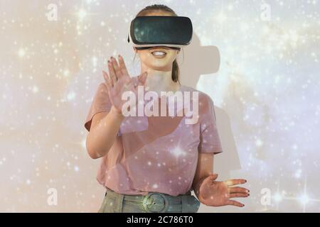 Lächelnde junge Frau, die mit glitzerndem Sternenhimmel gegen die Projektionsleinwand steht, während sie Astronomie mit dem Virtual Reality Simulator studiert Stockfoto