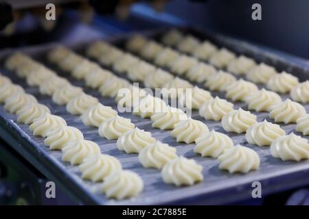 Butter wirbeln geschlagene Shortbread-Kekse auf dem Tablett an der Produktionslinie. Selektiver Fokus. Stockfoto