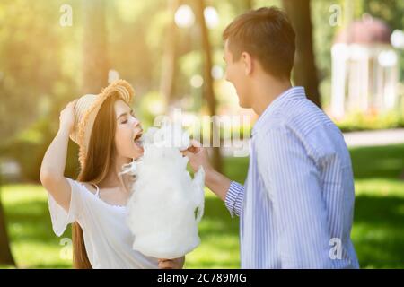 Romantische Zeiten zusammen. Happy Millennial paar essen Süßigkeiten Zahnseide zusammen im Sommer im Freien Stockfoto
