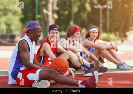 Diverse Profisportler, die nach dem Basketballspiel auf dem Platz im Freien Pause machen, Platz zum Kopieren Stockfoto