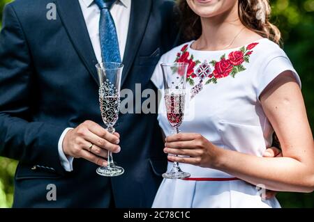 Gläser roten Champagner in den Händen des Brautpakts Stockfoto