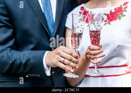 Gläser roten Champagner in den Händen des Brautpakts Stockfoto