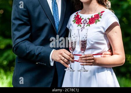 Gläser roten Champagner in den Händen des Brautpakts Stockfoto