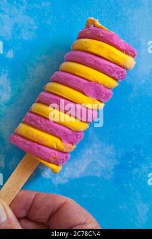 Halten Barratt Fruit Salat Himbeere & Ananas Geschmack Ice Lolly auf blau gemusterten Hintergrund Stockfoto