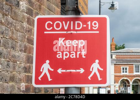 Ein Schild, das vor Covid-19 warnt und die Leute anweist, Abstand zu halten. Stockfoto