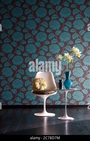 Aufnahme von eleganten Stuhl mit Blumenvase auf Beistelltisch vor floralen Tapeten Wand Stockfoto