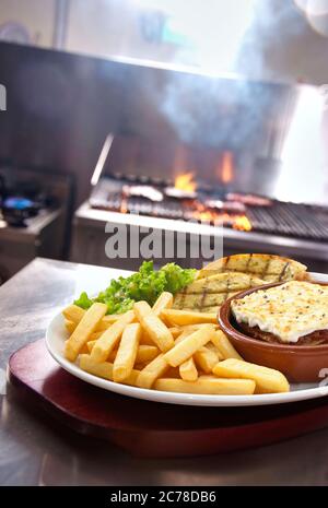 Schuss einer Lasagne verdi mit Chips und Beilagen Salat und Knoblauchbrot serviert in einem Teller in der Restaurantküche Stockfoto