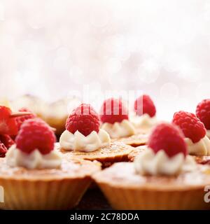 Leckere Cupcakes mit Sahnetüpfeln und Erdbeeren darauf Stockfoto