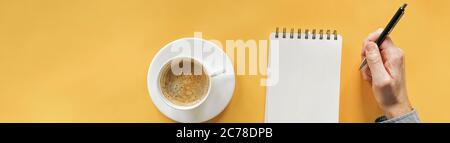 Hand des Mannes, Stift, Notizblock und Kaffee. Bannerformat mit Platz für Text. Arbeitsplatz Draufsicht Stockfoto