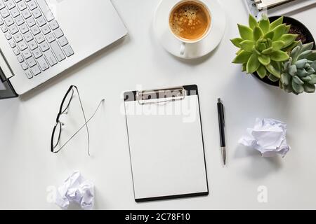 Arbeitsplatzkonzept. Clipboard-Mock-up auf dem Tisch mit Kaffee, Gläser, Laptop und zerknittertem Papier Stockfoto