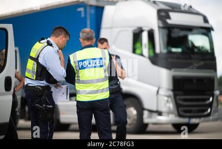 Unna, Deutschland. Juli 2020. Auf dem Parkplatz Kolberg auf der Autobahn 2 in Richtung Hannover prüfen Polizeibeamte die Papiere eines LKW-Fahrers. Die Landpolizei Unna führt zusammen mit dem Landesamt für Bildung, Weiterbildung und Personalwesen (LAFP) und Zoll umfangreiche LKW-Kontrollen durch. Der Schwerpunkt der Kontrollen liegt auf der Einhaltung der Sozialvorschriften. Quelle: Jonas Güttler/dpa/Alamy Live News Stockfoto