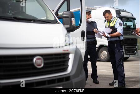 Unna, Deutschland. Juli 2020. Zwei Polizisten prüfen auf dem Parkplatz Kolberg auf der Autobahn 2 in Richtung Hannover die Papiere eines Lkw-Fahrers. Die Landpolizei Unna führt zusammen mit dem Landesamt für Bildung, Weiterbildung und Personalwesen (LAFP) und Zoll umfangreiche LKW-Kontrollen durch. Der Schwerpunkt der Kontrollen liegt auf der Einhaltung der Sozialvorschriften. Quelle: Jonas Güttler/dpa - ACHTUNG: Informationen zu den Papieren wurden aus rechtlichen Gründen verpixelt/dpa/Alamy Live News Stockfoto
