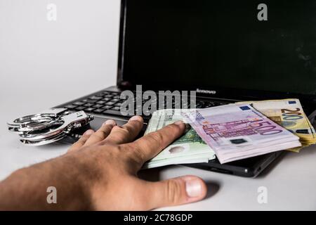 Bamberg, Deutschland 13. Juli 2020: Symbolische Bilder - 2020 mehrere Tausend Euro in bar mit den Werten von 500 Euro, 200 Euro, 100 Euro und 50 Euro liegen auf einem Laptop mit Handschellen, Cyberkriminalität, Cyberkriminalität, - weltweit Stockfoto