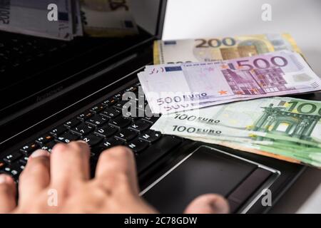 Bamberg, Deutschland 13. Juli 2020: Symbolische Bilder - 2020 mehrere Tausend Euro in bar mit den Werten von 500 Euro, 200 Euro, 100 Euro und 50 Euro liegen auf einem Laptop mit Handschellen, Cyberkriminalität, Cyberkriminalität, - weltweit Stockfoto