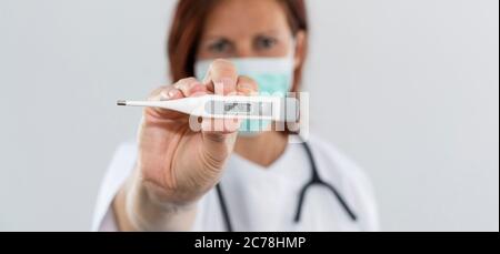 Frau Arzt hält Thermometer Stockfoto