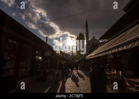 SARAJEVO, BOSNIEN UND HERZEGOWINA - 17. APRIL 2017: Straße mit Touristen und einem Moschee-Minarett im Stadtteil Bascarsija. Bascarsija ist ein Symbol von Sa Stockfoto