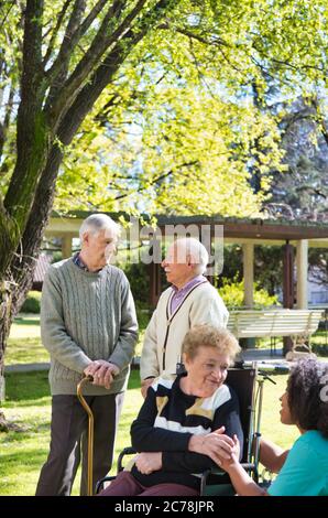 Glückliche Gruppe von älteren Menschen, die sich im Garten entspannen. Stockfoto