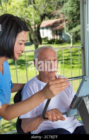 Frau, die älteren Mann im Fitnessstudio unterstützt. Stockfoto